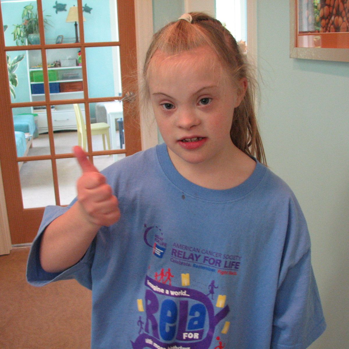 Girl giving thumbs up while wearing a Relay for Life T-shirt, showing support and confidence.
