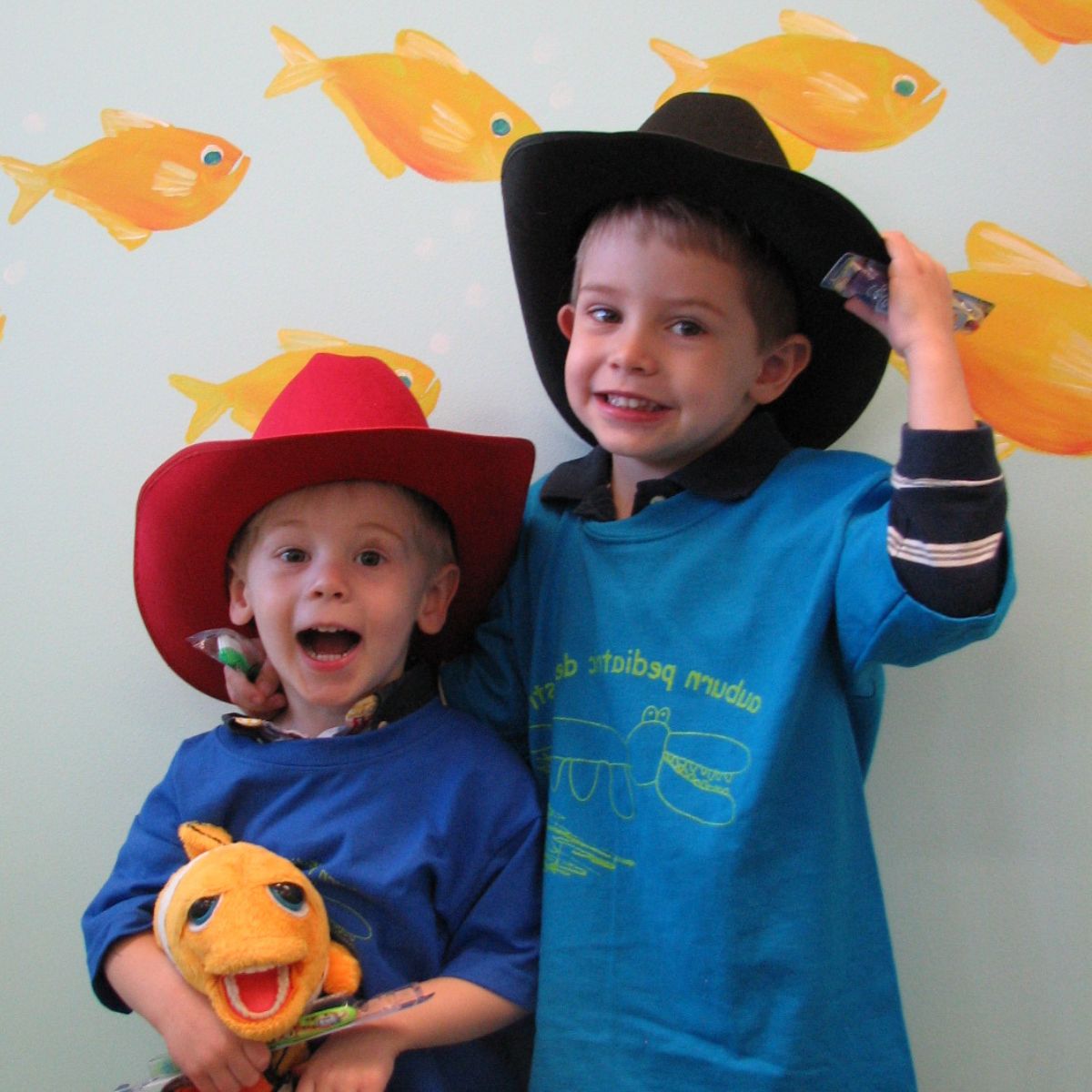 Two young kids wearing cowboy hats and smiling