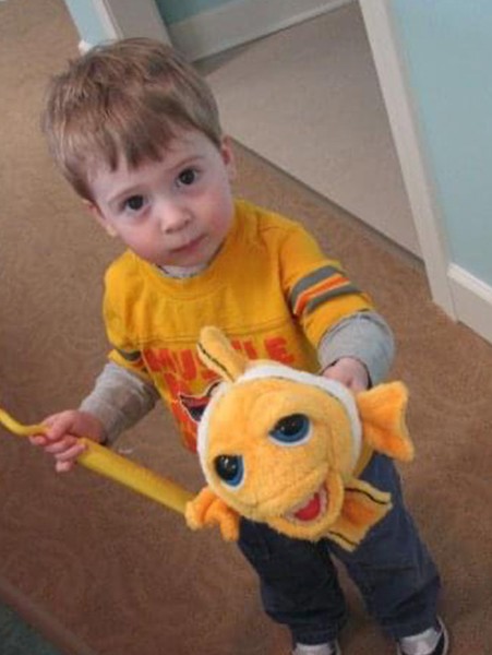 Service page content image 4 Toddler holding plush fish toy and smiling, showing comfort in a friendly dental office setting.